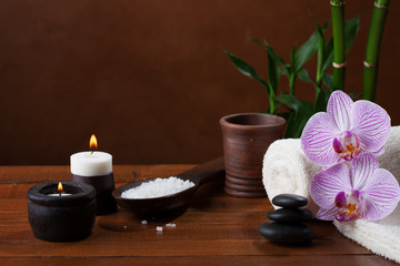 Spa setting with sea salt, candles, towels, stones and orchids.
