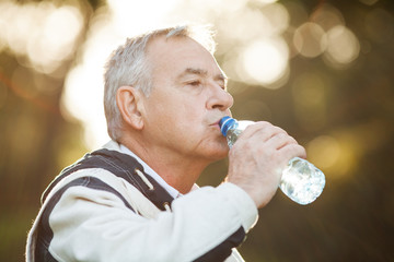 Senior man drinking water in park