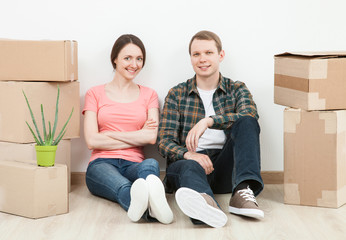 Happy young man and woman sitting near  cardboard boxes