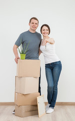 Fototapeta na wymiar Happy young man standing near cardboard boxes, his smiling wife