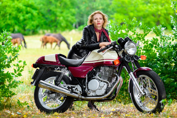 Naklejka na ściany i meble Biker girl in leather jacket on a motorcycle over the background
