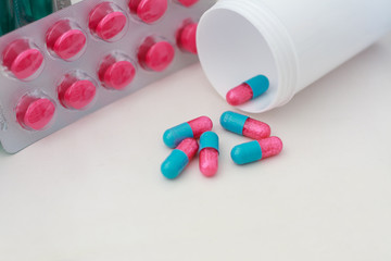 Pills spilling out of pill bottle with medicine background