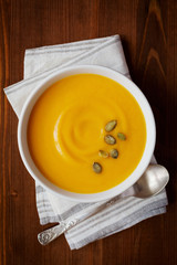 Fresh autumn pumpkin cream soup in bowl, dietary vegetable soup, top view