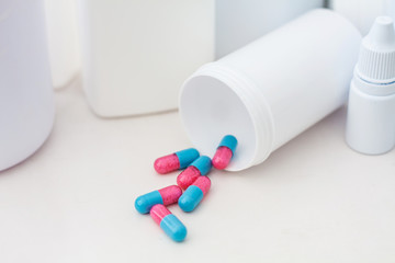 Pills spilling out of pill bottle with medicine background