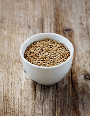 Bowl of dry lentils on a wooden background