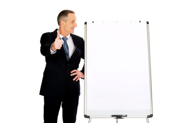 Male executive with ok sign near flip chart