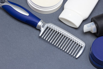 Hair styling products with comb on gray background