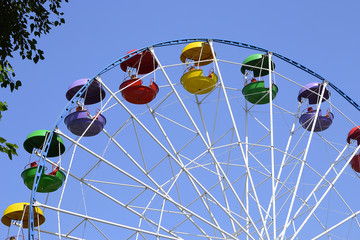 Ferris wheel in  Gagarin Park, Novokuznetsk, Russia.

It's the upper part of the ferris wheel with multi-colored booths against the bright blue sky.