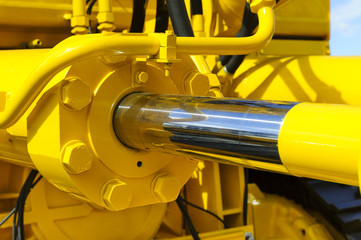 Hydraulic piston system for bulldozers, tractors, excavators, chrome plated cylinder shaft of yellow machine, construction heavy industry detail, selective focus  - 89763620