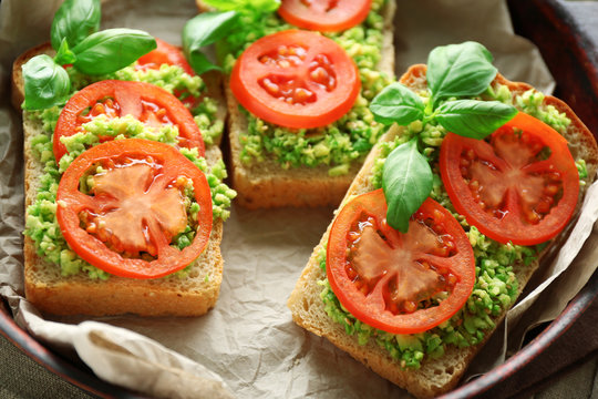 Vegan sandwich with avocado and vegetables on pan, close-up
