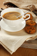 Cup of coffee with cookie on table, closeup