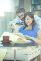 Fototapeta premium Couple at home websurfing on internet, shot through window