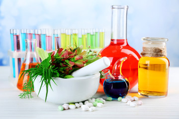 Herbs in mortar, test tubes and pills,  on table, on light background