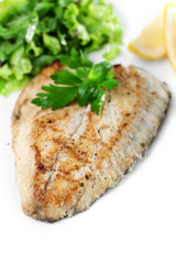 Dish of fish fillet with greens and lemon on plate close up