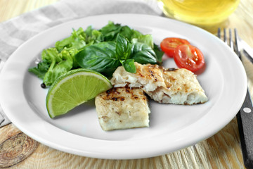 Dish of fish fillet with salad and lime on table close up