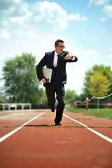businessman looking wrist watch watch running on athletic track in stress