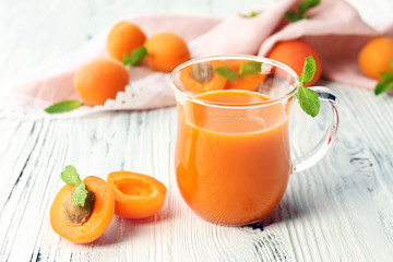 Cup of apricot juice and fresh fruits on table close up