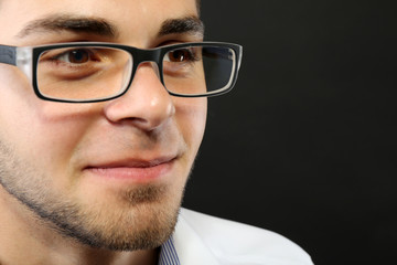 Attractive young man with glasses on gray background