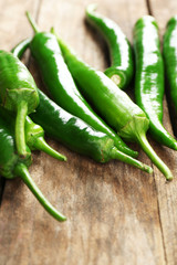 Green hot peppers on wooden table close up