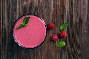 Glass of raspberry milk shake with berries on wooden background