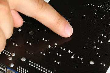 Finger points to motherboard, closeup