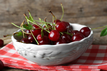 Cherries in bowl, on wooden background