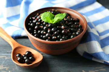 Ripe blackcurrant in bowl on wooden background