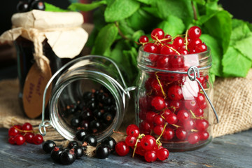 Ripe forest berries in glass jar  on wooden background