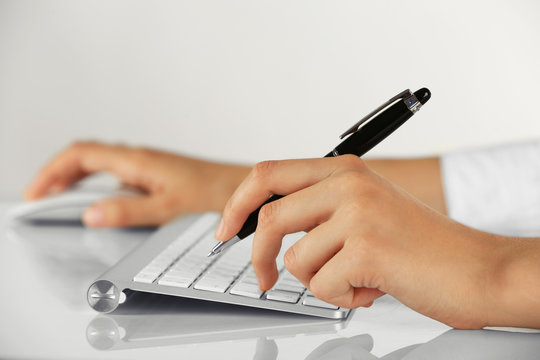 Female hands holding pen and computer mouse on light background