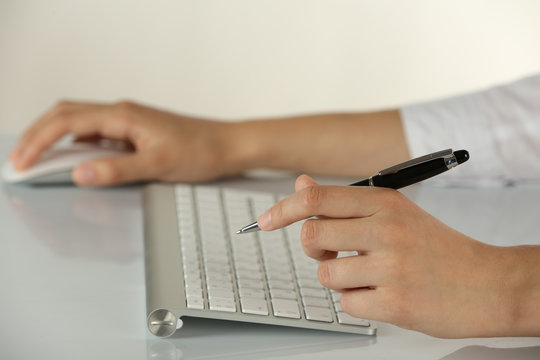Female hands holding pen and computer mouse on light background