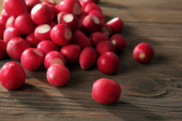 Heap of fresh radishes on wooden table close up background