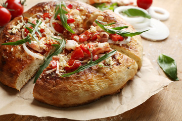 Greek homemade pizza with ham,onion, roasted tomato, creamy feta on wooden table background