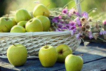 Naklejka na ściany i meble Green apples with bouquet of wildflowers on wooden table, closeup