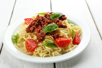 Spaghetti Bolognese on white plate, on color wooden background