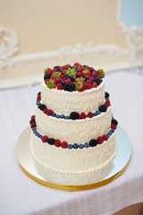 Beautiful wedding cake with berries on wooden table