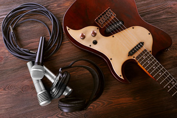 Naklejka premium Electric guitar with microphones and headphones on wooden table close up
