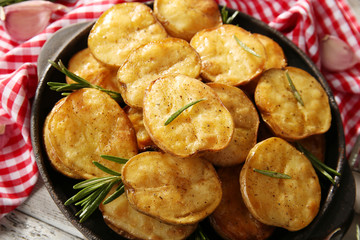Delicious baked potato with rosemary in frying pan on table close up