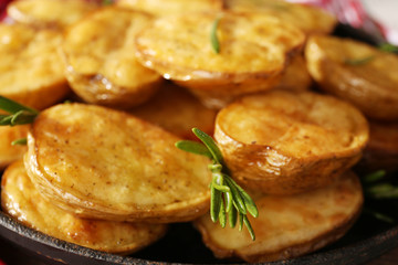 Delicious baked potato with rosemary in frying pan close up