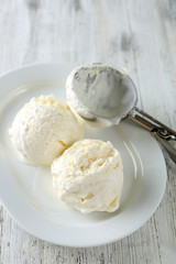 Delicious vanilla ice cream on plate, on wooden background