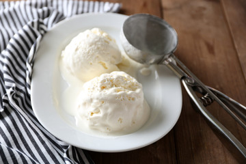 Delicious vanilla ice cream on plate, on wooden background