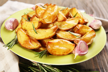 Baked potato wedges on wooden table, closeup