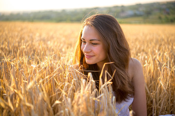 girl looks at the wheat field at sunset