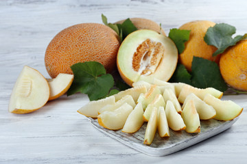 Ripe melons with green leaves on wooden table close up