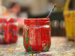 Old jar covered with red paint and brush - tools for painter