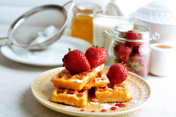 Sweet homemade waffles with fresh strawberries on plate, on light background