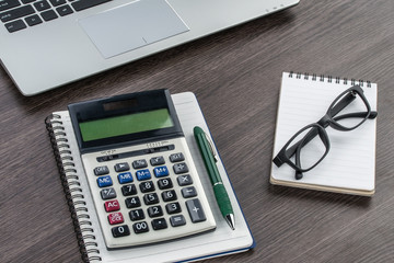 laptop, notebook and pen with calculator on the desk