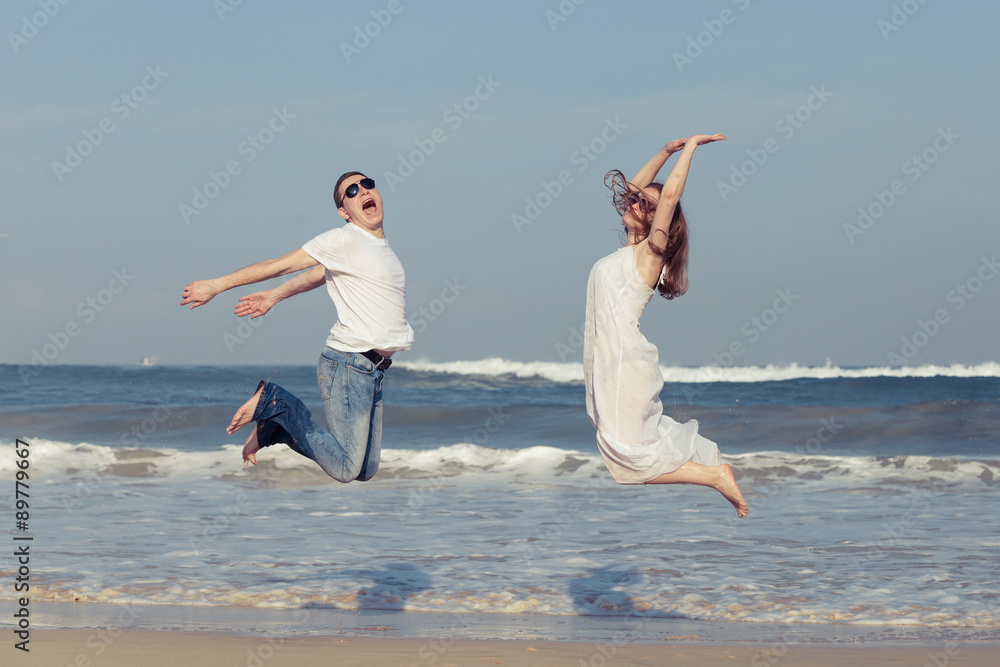 Wall mural loving couple running on the beach at the day time.