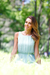 young woman in blue dress sitting on grass