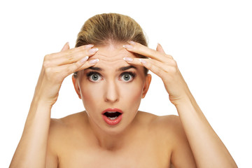 Young woman checking wrinkles on her forehead