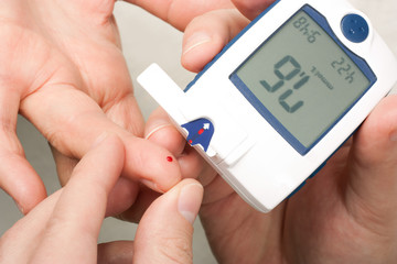 Diabetic is doing a glucose level finger blood test 